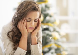 Portrait of stressed young woman near christmas tree